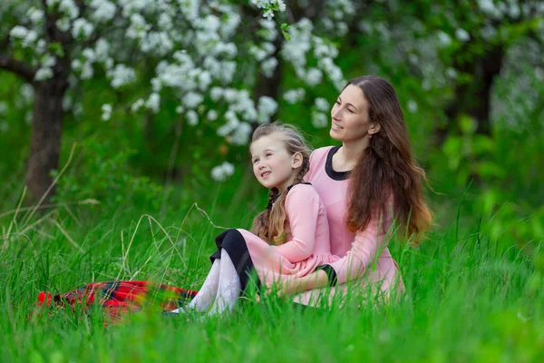 Мать и дочь сидят в яблоневом саду — стоковое фото