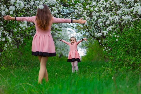 Мать и дочь гуляют по цветущему саду — стоковое фото