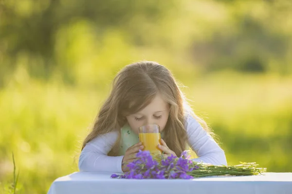 Girl drinking juice sitting at the table — Stock Photo, Image