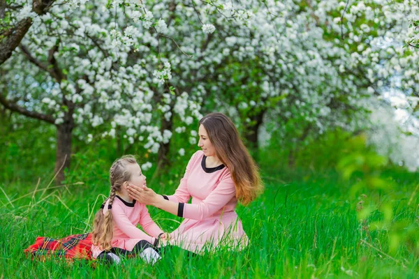 Мать и дочь сидят в яблоневом саду — стоковое фото