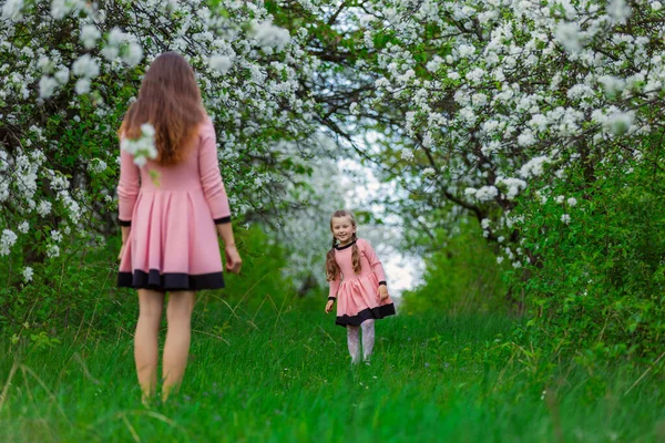 Mãe e filha estão caminhando pelo jardim florescente — Fotografia de Stock