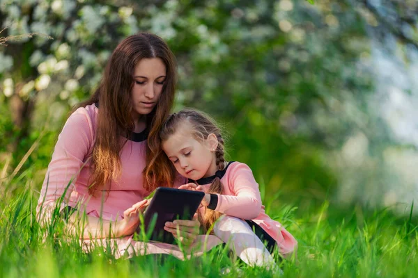 Mor med dotter och tablett i naturen — Stockfoto