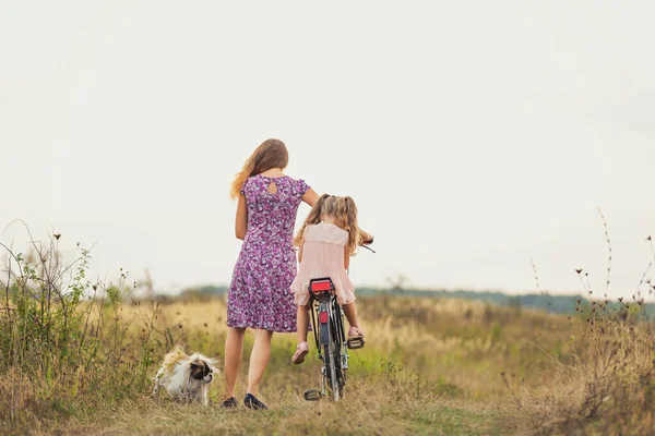 Madre e hija caminando con una bicicleta y un perro —  Fotos de Stock