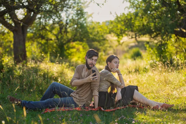 Paar zitten op het gazon en kijken naar hun telefoons — Stockfoto