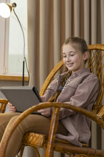 Chica con una tableta sentada en una mecedora — Foto de Stock