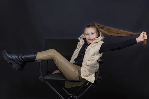 Ragazza tenendo i capelli mentre si siede su una sedia — Foto Stock