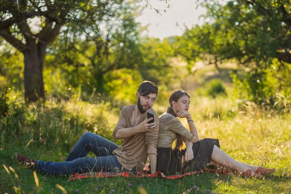 Paar zitten op het gazon en kijken naar hun telefoons — Stockfoto