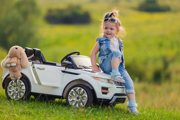 Mädchen sitzt auf der Motorhaube eines Kinderwagens — Stockfoto
