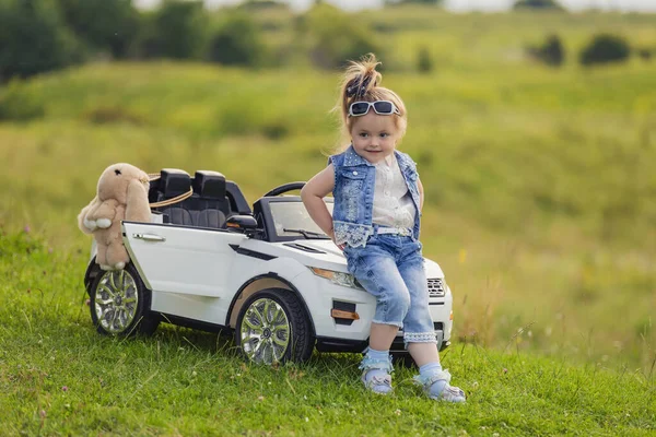 Girl sitting on the hood of a childrens car — Stock Photo, Image