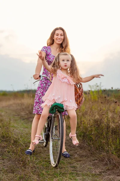 Mamá monta a su hija en una bicicleta —  Fotos de Stock