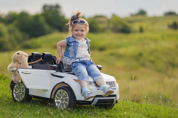 Mädchen sitzt auf der Motorhaube eines Kinderwagens — Stockfoto