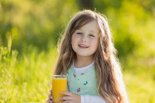 Child sits at a table on which there is a glass of juice — Stock Photo, Image