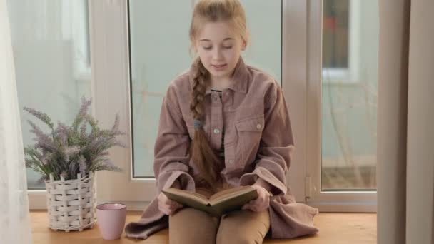 Meisje met een boek in de buurt van het venster — Stockvideo