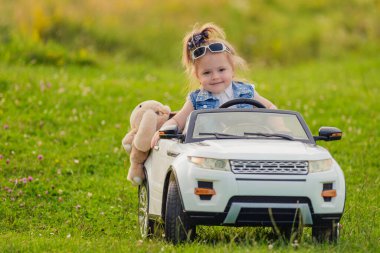 Küçük kız bir çocuk arabasına biniyor.