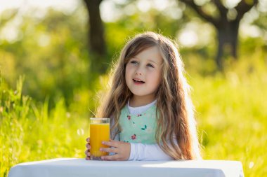 Çocuk bir bardak meyve suyu olan bir masaya oturur.