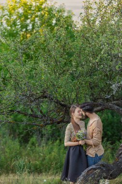 Bir ağacın yanında kucaklaşan çift.