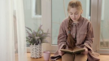 Kız pencerenin yakınındaki bir kitapla