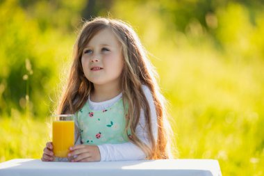 Çocuk bir bardak meyve suyu olan bir masaya oturur.