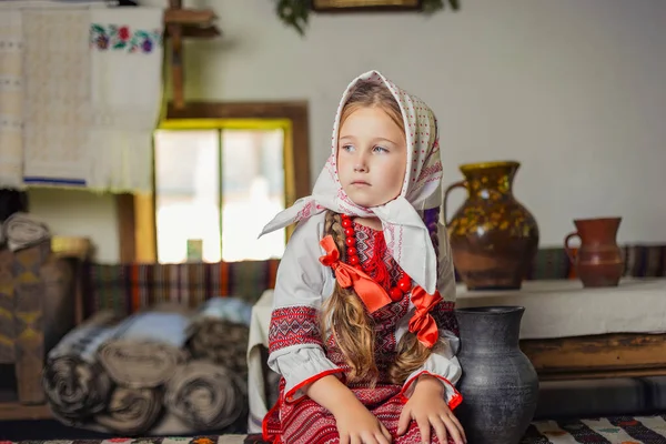 Flicka i ukrainska nationaldräkt sitter på en bänk — Stockfoto