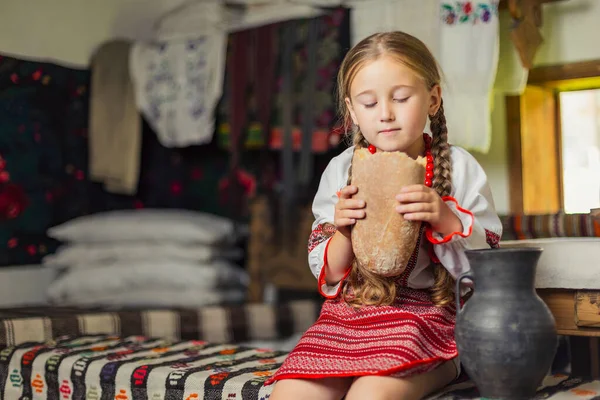 Girl in Ukrainian national costume eats bread — Stock Photo, Image