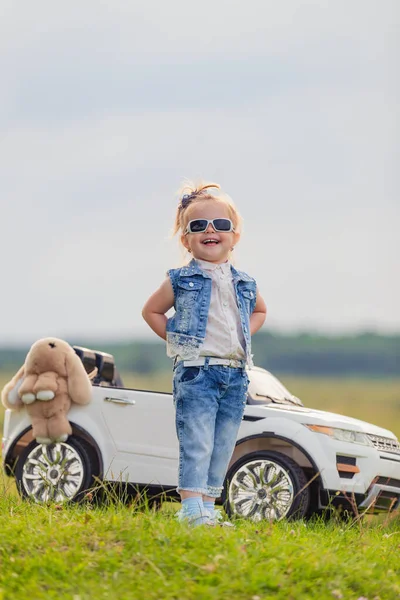 Girl in sunglasses stands in front of a car — Stock Photo, Image