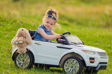 Küçük kız bir çocuk arabasına biniyor.