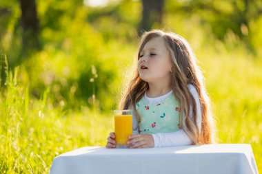 Çocuk bir bardak meyve suyu olan bir masaya oturur.