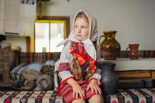Menina no traje nacional ucraniano senta-se em um banco — Fotografia de Stock