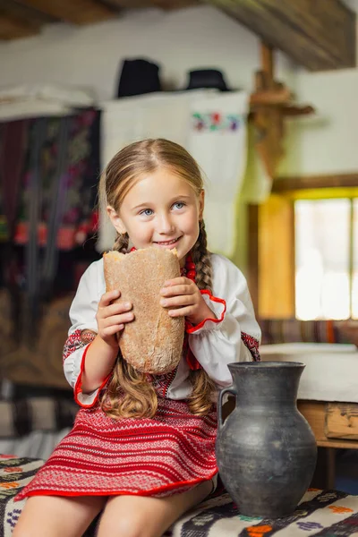 Chica en ucraniano traje nacional come pan —  Fotos de Stock