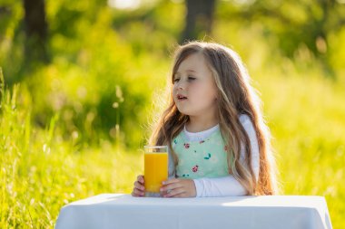 Çocuk bir bardak meyve suyu olan bir masaya oturur.