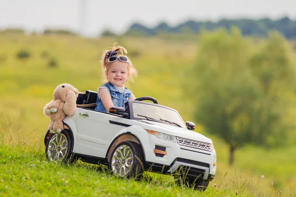 Little girl rides in a childrens car — Stock Photo, Image