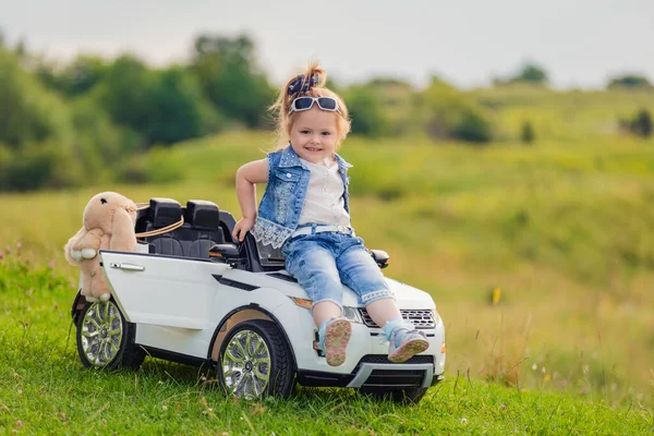 Girl sitting on the hood of a childrens car — Stock Photo, Image