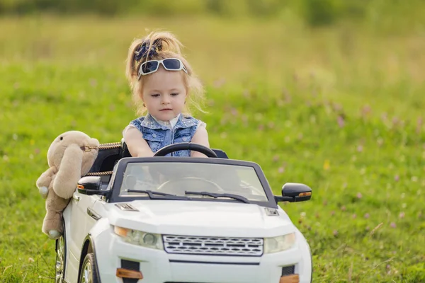 Liten flicka rider i en barnbil — Stockfoto