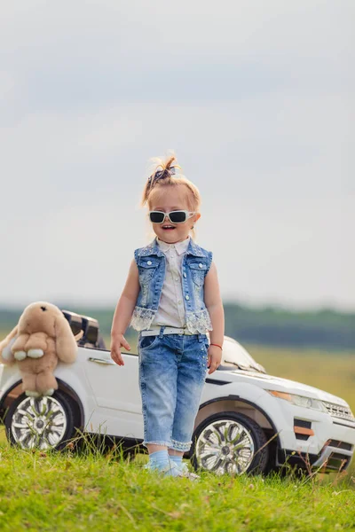 Girl in sunglasses stands in front of a car — Stock Photo, Image