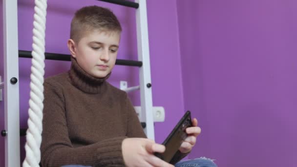 Мальчик, играющий по телефону — стоковое видео