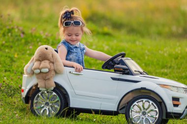 Küçük kız bir çocuk arabasına biniyor.