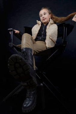 # Kız sandalyeye oturmuş, saçlarını tutuyor #