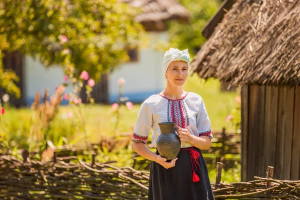 Mujer en traje nacional ucraniano con una jarra en sus manos — Foto de Stock