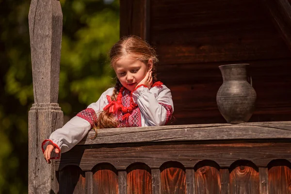 Girl in a Ukrainian dress stands near a jug — ストック写真