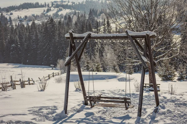 Holzschaukel vor der Kulisse schneebedeckter Berge — Stockfoto