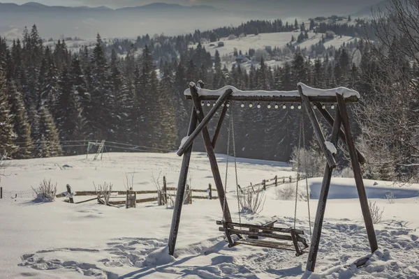 Holzschaukel vor der Kulisse schneebedeckter Berge — Stockfoto