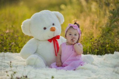 Çocuk büyük bir ayının yanında oturuyor.