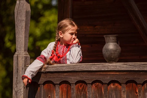 Meisje in een Oekraïense jurk staat in de buurt van een kan — Stockfoto