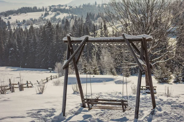 Holzschaukel vor der Kulisse schneebedeckter Berge — Stockfoto