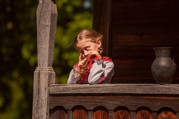 Meisje in een Oekraïense jurk staat in de buurt van een kan — Stockfoto