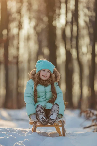 Liten flicka sitter i en släde — Stockfoto