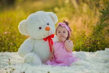 Çocuk büyük bir ayının yanında oturuyor.