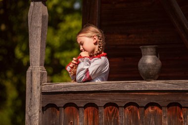 Ukrayna elbiseli kız bir sürahinin yanında duruyor.