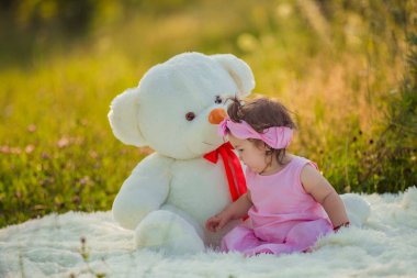 Çocuk büyük bir ayının yanında oturuyor.