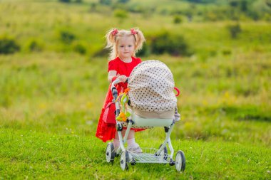 Oyuncak bebek arabası olan kız.